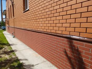 Готовая отделка длинного цоколя коттеджа в Полково красным гибким кирпичом с защитным отливом